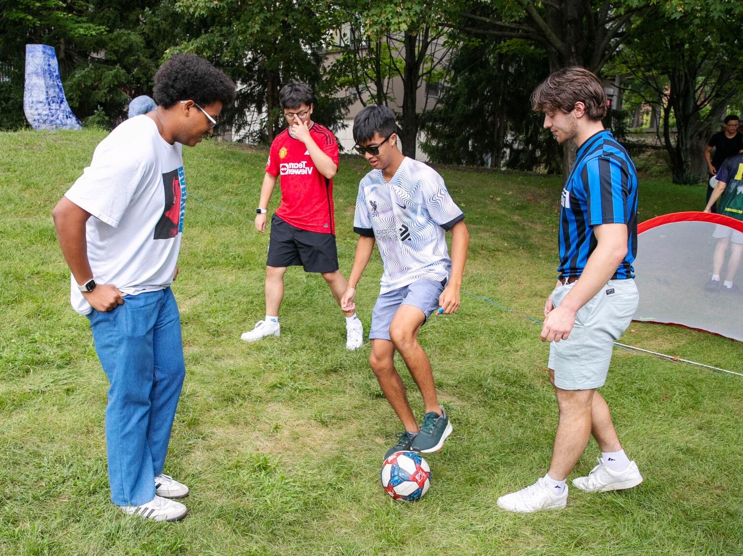 Four students play soccer on Skidmore's South Lawn.
